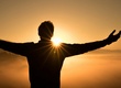 Mann mit ausgebreiteten Armen im Sonnenuntergang
